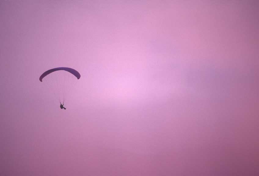 Paragliding Photos Jim Donaldson flying near Oceanside as the sun sets beyond the fog.