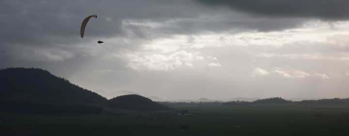 Paraglider flying near dark clouds